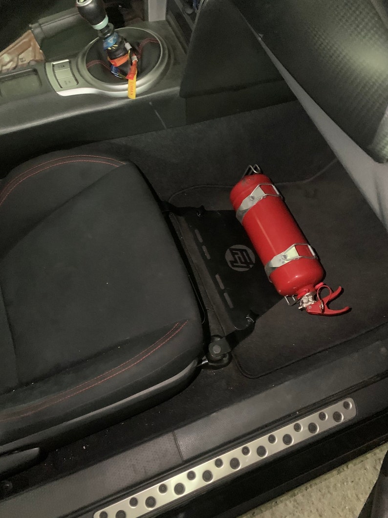 Toyota GT86 fire extinguisher holder bracket mounted on OEM seat rails. Ensure safety with easy access to the fire extinguisher while driving. A reliable addition to your GT86 for emergency situations