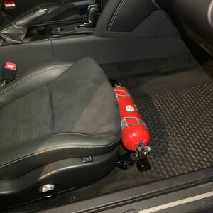 Nissan GTR R35 fire extinguisher holder bracket mounted on OEM seat rails. Ensure safety with this easy-to-access and sturdy bracket for emergencies. Perfect fit for your GTR R35