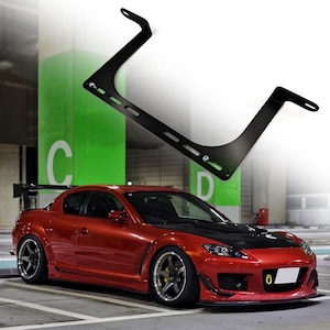 May include: A red sports car with a black aftermarket roll cage. The car has a black front bumper and a black rear diffuser. The car is parked in a garage.