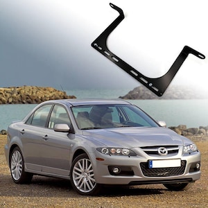 Op de afbeelding: Een zilveren sedan met een zwarte voorbumper en een zwarte grille. De auto heeft een zwart kenteken met de letters "D" en "D" erop. De auto staat geparkeerd op een grindweg.