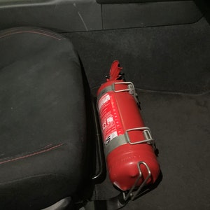 Toyota GT86 fire extinguisher holder bracket mounted on OEM seat rails. Ensure safety with easy access to the fire extinguisher while driving. A reliable addition to your GT86 for emergency situations