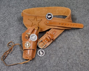May include: A brown leather gun belt with a silver buckle and a holster for a pistol. The belt has a star design and is decorated with silver conchos.