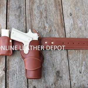 Könnte beinhalten: Ein brauner Ledergürtel mit einem Pistolenholster und zwei Magazintaschen. Der Gürtel ist mit dem Text "ONLINE LEATHER DEPOT" geprägt.