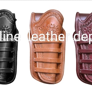 Op de afbeelding: Drie leren holster voor een pistool, een zwarte, een bruine en een bordeauxrode. Elke holster heeft een decoratief bloemenpatroon en vier riemen.