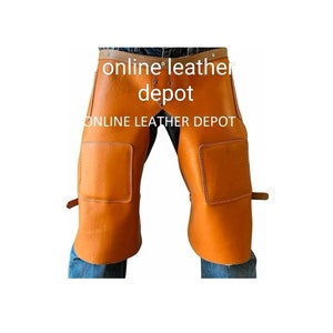 Könnte beinhalten: Eine orangefarbene Leder-Arbeitshose mit verstärkten Kniepatches. Die Hose hat einen Gürtel- und Schnallenverschluss an der Taille und verstellbare Riemen. Der Text "online leather depot" ist auf der Hose aufgedruckt.