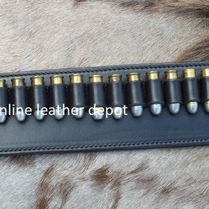 May include: A black leather belt with a row of silver bullet loops. The belt is labeled "online leather depot".