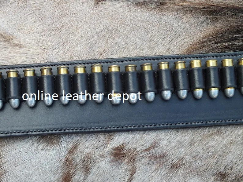 May include: A black leather belt with a row of silver bullet loops. The belt is labeled "online leather depot".