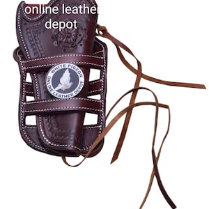 Puede incluir: Funda de cuero marrón con un diseño cosido blanco y una placa de metal que dice "White Pigeon Online Leather Depot".