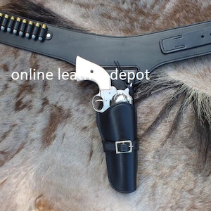 May include: A black leather gun belt with a silver buckle and a holster for a pistol. The belt is worn on a horse's back. The text "online leather depot" is visible in the image.