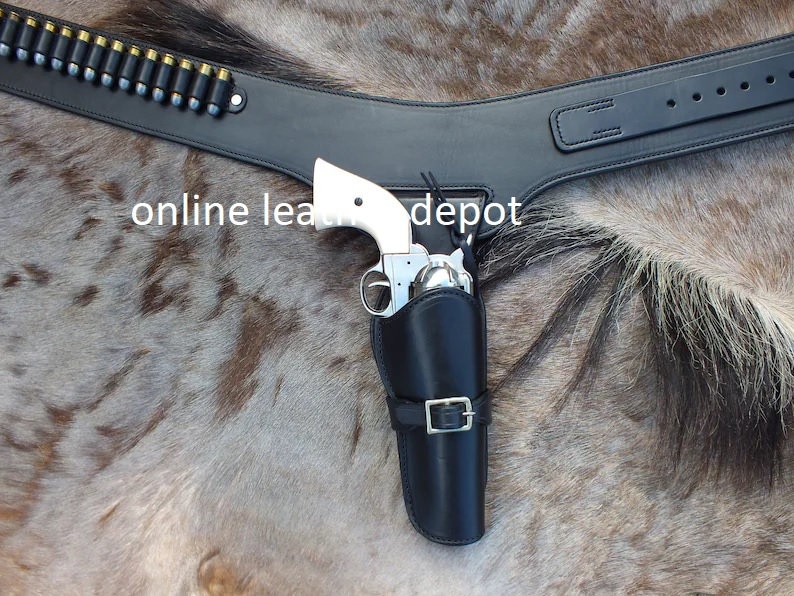 May include: A black leather gun belt with a silver buckle and a holster for a pistol. The belt is worn on a horse's back. The text "online leather depot" is visible in the image.