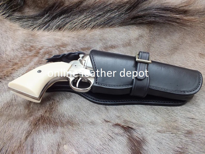 May include: A black leather holster with a silver revolver inside. The holster has a buckle and is designed for a right-handed shooter. The text "online leather depot" is visible on the holster.