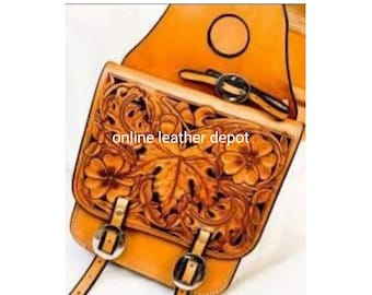 May include: A brown leather saddle bag with intricate floral tooling. The bag has two buckles and a strap. The bag is labeled "online leather depot".