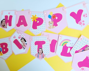 May include: Pink and white banner with the words "Happy Birthday" in pink letters. Each letter has a different design, including a sun, a teddy bear, a rainbow, and paw prints. There are also photos of children on some of the letters.