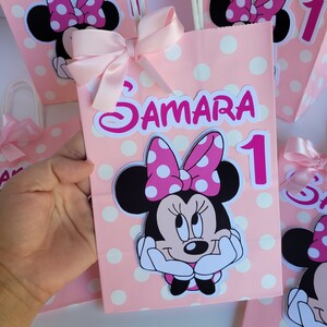 May include: Pink and white polka dot gift bags with a Minnie Mouse character, a pink bow, and the name "Samara" and the number "1" printed on them.