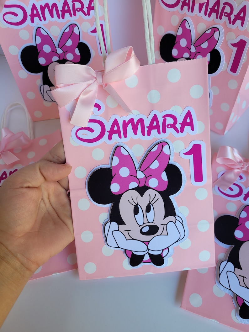 May include: Pink and white polka dot gift bags with a Minnie Mouse character, a pink bow, and the name "Samara" and the number "1" printed on them.