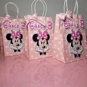 May include: Three pink and white polka dot gift bags with white handles and pink bows. Each bag has a Minnie Mouse character sticker with the name "Grace 3" on the front.