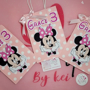 May include: Three pink and white polka dot gift bags with Minnie Mouse character cutouts and the name "Grace 3" on each bag.