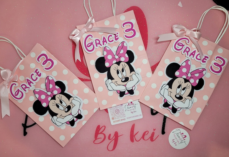 May include: Three pink and white polka dot gift bags with Minnie Mouse character cutouts and the name "Grace 3" on each bag.