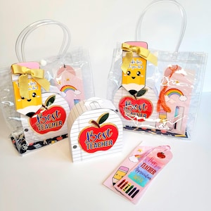 Puede incluir: Bolsas transparentes llenas de regalos de agradecimiento para profesores. Cada bolsa contiene una etiqueta de regalo con forma de lápiz con un lazo dorado, un marcapáginas y una caja con un diseño de manzana que dice "Best Teacher".