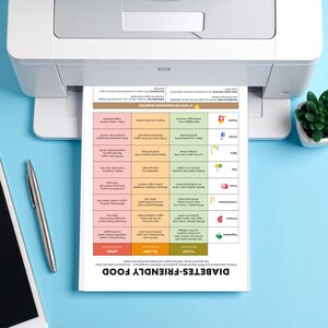 May include: A printed document titled "DIABETES-FRIENDLY FOOD" is emerging from a white printer. The document is a colorful chart with food categories and dietary guidelines. A pen and a tablet are on a blue surface.