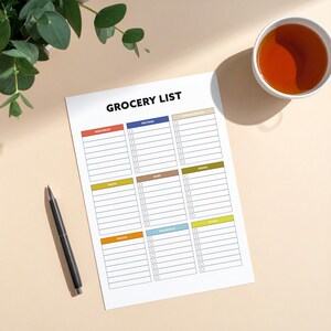 May include: A white grocery list notepad with the title "GROCERY LIST" in black. The notepad is divided into sections for vegetables, proteins, carbohydrates, fruits, dairy, drinks, snacks, and other. A black pen and a cup of tea are also in the image.