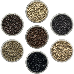 Peut inclure: Sept petits bols remplis de micro-perles de différentes nuances de brun, noir et beige. Les perles sont utilisées pour les extensions de cheveux.