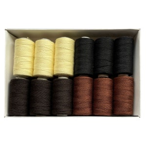 May include: A box of 12 spools of thread in three colors: cream, black, and brown. The spools are arranged in three rows of four.