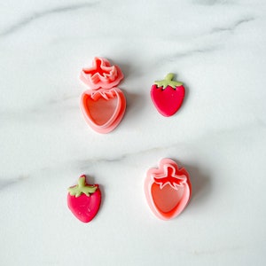 Peut inclure: Quatre emportes-pièces en plastique rose en forme de fraise, deux sont des fraises entières et deux ne sont que le dessus de la fraise.