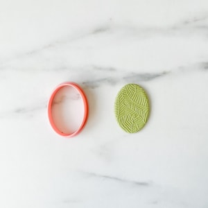 Peut inclure: Un emporte-pièce en plastique rose et un cercle de fondant vert avec un motif de feuilles.
