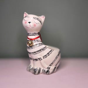 May include: A set of three ceramic mugs with a speckled, matte finish. The mugs are in shades of cream, light gray, and dark gray. Each mug has a simple, minimalist design and a rounded handle.