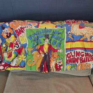 May include: A colorful circus-themed quilt featuring clowns, a ringmaster, a tiger, and the text "Ringling Bros. Barnum & Bailey Circus." The quilt has a patchwork design with red, blue, yellow, and green panels.