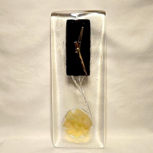 May include: A rectangular glass clock with a black clock face and gold-colored hands. The clock has a clear glass body with a yellow circular design at the bottom. The clock is approximately 10 inches tall.