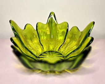 May include: A green glass bowl with a flower petal design. The bowl is a vibrant shade of green and has a textured surface. The petals extend outwards, creating a unique and decorative shape. This bowl is perfect for serving or as a decorative piece.