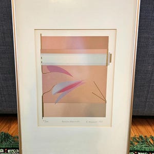 May include: A framed abstract art print with a geometric design in shades of pink, brown, and white. The print is titled "French Memorial" and signed "E. Dagnan 1983".