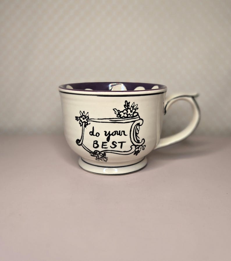May include: A white ceramic mug with a black handle and the text "But First, Coffee" in a bold, black font. The mug is set against a blurred background, suggesting a cozy setting. The mug appears to be approximately 4 inches tall.