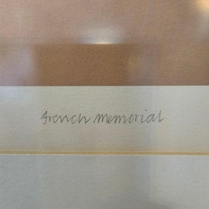 May include: A close-up of a white card with the text "French Memorial" written in black ink.