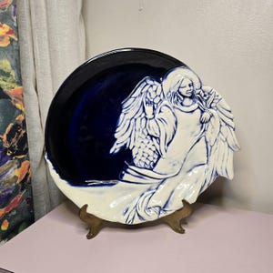 May include: A set of three ceramic mugs with a speckled, matte finish. The mugs are in shades of cream, light gray, and dark gray. Each mug has a simple, minimalist design and a rounded handle.