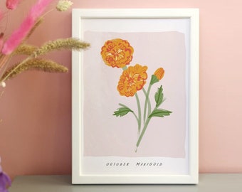 May include: A white framed wall art print featuring a botanical illustration of two orange marigold flowers and a bud on a light pink background. The text OCTOBER MARIGOLD is printed in black at the bottom of the illustration within the white frame.