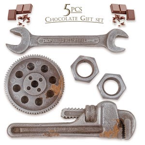 Puede incluir: Un juego de regalo de chocolate con cinco piezas en forma de herramientas, incluyendo una llave, un engranaje y tuercas. El juego también incluye barras de chocolate y virutas de chocolate. Se muestra el texto "5 PCS CHOCOLATE GIFT SET".
