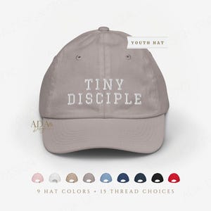 May include: A light taupe baseball cap with the embroidered text "TINY DISCIPLE" in white. The image shows a variety of hat colors and thread choices. The text "YOUTH HAT" is also visible.