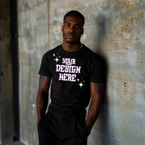 May include: A black t-shirt with the text "YOUR DESIGN HERE" in white with purple outlines and small white stars on the front.