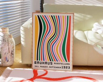 May include: A framed poster with a colorful abstract design of wavy lines in red, yellow, green, blue, pink, and black. The poster has the text "BAUHAUS AUSSTELLUNG JULI, AUGUST, SEPTEMBER 1923".