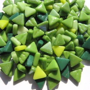 May include: A collection of small, triangular glass mosaic tiles in various shades of green and yellow. The tiles are in different sizes and shapes, creating a textured and colorful display. Ideal for craft projects.
