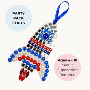Puede incluir: Un kit de manualidades en forma de cohete de madera decorado con detalles azules, rojos, blancos y espejados. El kit incluye una cinta azul para colgar. El texto de la imagen dice "Party Pack 10 Kits" y "Ages 4-10 *Adult Supervision Required."