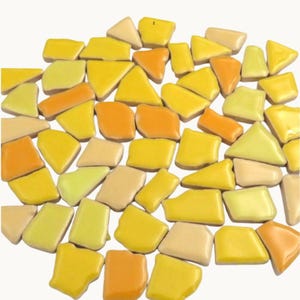 May include: A collection of irregularly shaped ceramic tiles in shades of yellow, orange, and cream. The tiles vary in size and shape, with a glossy finish. The arrangement is scattered, creating a mosaic effect. Ideal for craft projects or home decor.