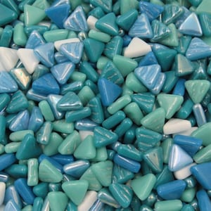 May include: A collection of glossy, colorful mosaic tiles in shades of blue, teal, and white. The tiles are primarily triangular and rectangular shapes, creating a textured, eye-catching surface. The mosaic pieces are scattered, creating a visually appealing pattern.