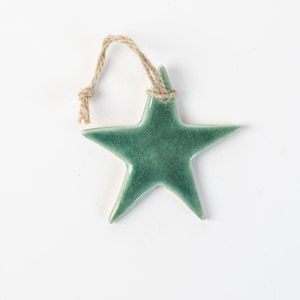 Peut inclure: Ornement en forme d'étoile de couleur teal, avec un effet craquelé. Suspendu par une boucle en corde de jute naturelle. Idéal pour les décorations de Noël ou d'intérieur.
