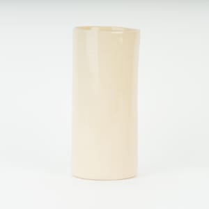 May include: A tall, cylindrical vase in a creamy off-white colour. The vase has a smooth, glossy finish and a simple, minimalist design. Suitable for displaying flowers or as a decorative accent.