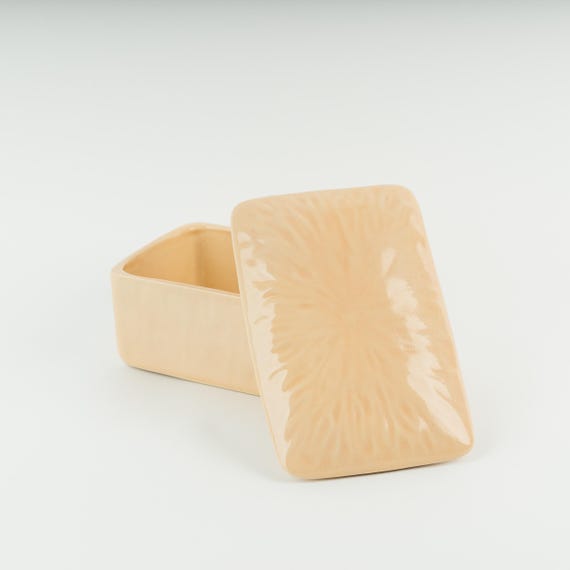 A wheel-thrown pale pink stoneware butter dish that turns a mundane countertop staple into a quiet little art object — the kind of thing that makes your kitchen feel curated.