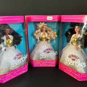 Puede incluir: Tres muñecas Barbie Summit en sus cajas originales. Cada muñeca viste un vestido blanco con corpiño dorado y chaqueta blanca. Las cajas son rosas y azules, con el logo de Barbie y texto en varios idiomas.